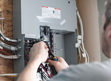 Service person rewiring a fuse box